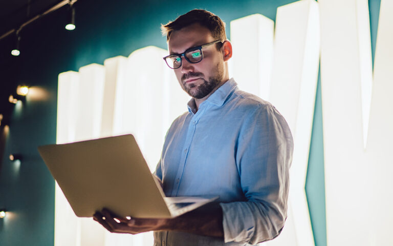 A imagem mostra um homem mexendo em um notebook. Ele pesquisa sobre os usos da inteligência artificial no recrutamento e seleção.