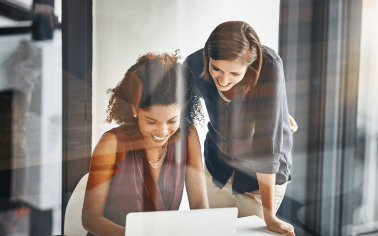 Imagem de capa do artigo sobre programas de trainee, com duas profissionais trabalhando juntas em um computador, simbolizando mentoria, desenvolvimento profissional e formação de futuras lideranças.