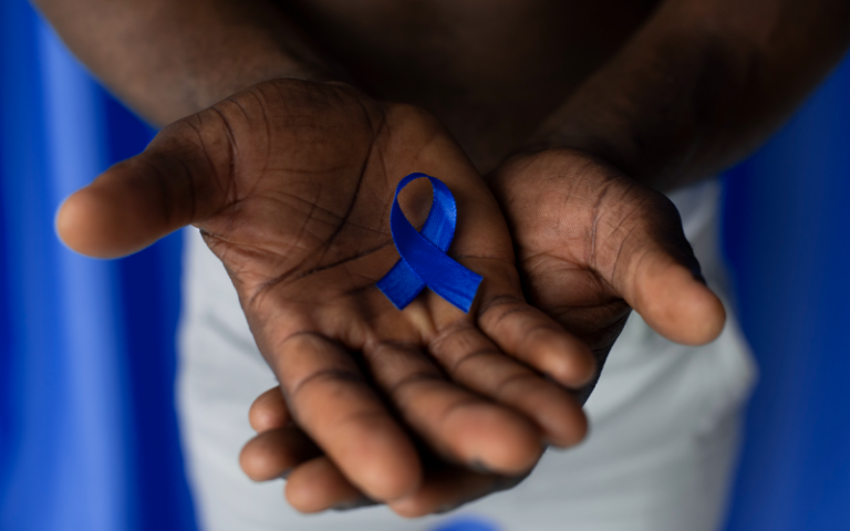 Imagem de duas mãos sobrepostas, com as palmas viradas para cima e um pequeno laço no centro, representando o Novembro Azul nas empresas.