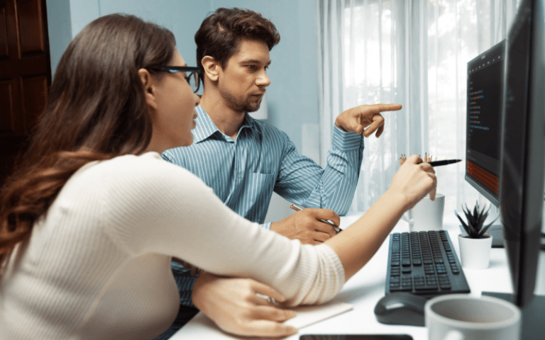 Imagem de capa para artigo sobre indicadores de treinamento e desenvolvimento, mostrando dois profissionais analisando informações em um computador, representando aprendizagem contínua e desenvolvimento de competências.