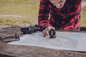 Homem buscando informação em um mapa. A imagem busca retratar, de forma lúdica, a dinâmica de caça ao tesouro aplicada no team building.