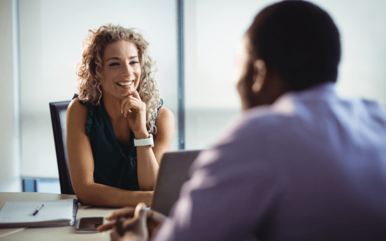 Recrutadora conversa com um candidato durante uma entrevista em um ambiente corporativo. A imagem ilustra uma entrevista comportamental estratégica, focada na avaliação de competências, experiências e habilidades interpessoais.