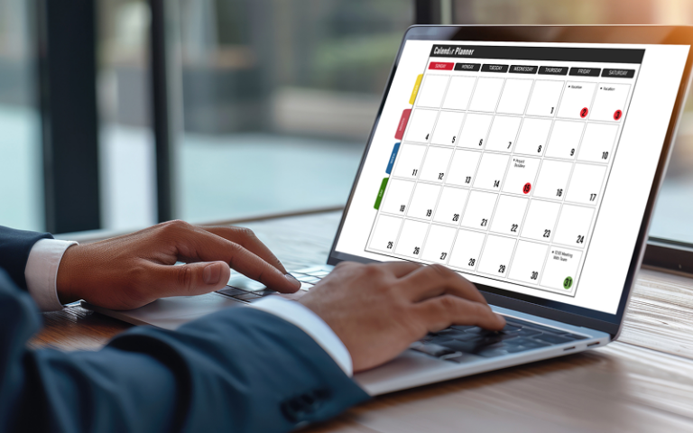 Pessoa usando computador portátil com calendário eletrônico em uma mesa de escritório, planejando tarefas e compromissos.
