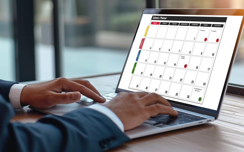 Pessoa usando computador portátil com calendário eletrônico em uma mesa de escritório, planejando tarefas e compromissos.