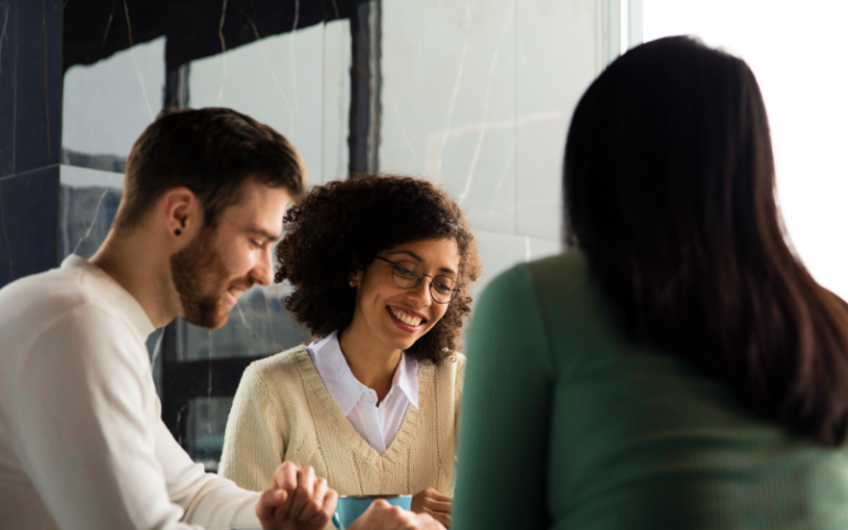 Imagem de capa de blog post sobre Selpe Advisory. Na foto, há três profissionais reunidos em uma mesa, com destaque para uma mulher ao centro sorrindo, transmitindo um ambiente acolhedor e colaborativo.
