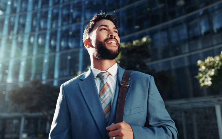 Imagem de capa para artigo sobre C-level. Profissional em traje corporativo elegante olha para o horizonte com expressão de confiança e sucesso, com a fachada de um prédio moderno ao fundo.