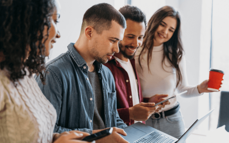 Jovens utilizam notebook e dispositivos móveis em um ambiente corporativo, ilustrando a busca por oportunidades e o processo de candidatura para um estágio remunerado.
