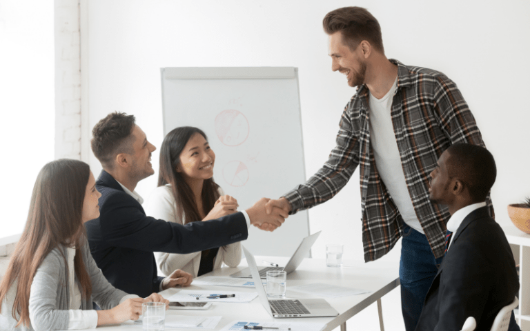 Profissional informal apertando a mão de um executivo em uma sala de reunião, simbolizando integração e colaboração entre talentos sob demanda e equipes internas.