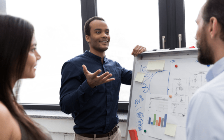 Imagem de capa de um blog post sobre accountability. Na foto, um profissional apresenta resultados e estratégias para sua equipe, demonstrando transparência e responsabilidade, enquanto duas pessoas observam atentamente.
