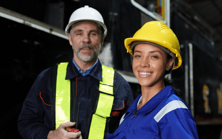 A imagem mostra dois trabalhadores operacionais em um ambiente industrial, possivelmente uma fábrica ou terminal logístico, fazendo referência aos desafios de atração de mão de obra operacional no Brasil.