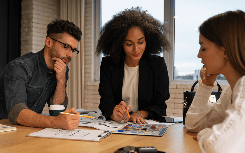 três profissionais participam de uma reunião em um ambiente corporativo, transmitindo a imagem de colaboração e trabalho em equipe no desenvolvimento de um workforce planning.